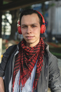 Stylish ethnic man in headphones outdoors
