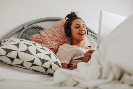 Smiling girl lying on bed using a laptop