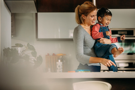 Mother and son enjoying while baking cookies in kitchen