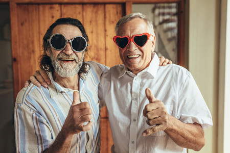 Retired friends with party eyewear giving thumbs up