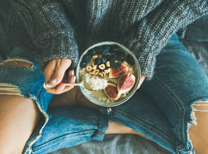 Woman in shabby jeans and sweater eating healthy breakfast