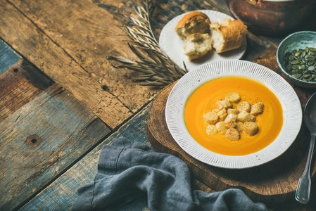 Warming pumpkin cream soup with croutons and seeds  selective focus