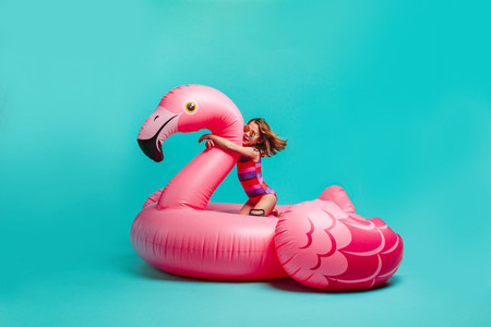 Girl on a giant inflatable flamingo imagining in the pool