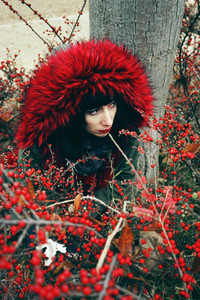 Portrait of a beautiful young brunette woman in red by a tree wi
