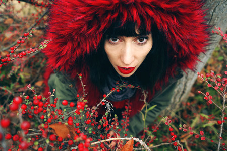 Portrait of a beautiful young brunette woman in red with hood wi