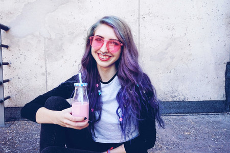 Happy beautiful teen with pink sunglasses drinks and enjoys a pi