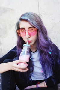 Happy beautiful teen with pink sunglasses drinks and enjoys a pi