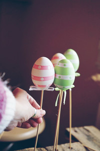 A beautiful close up of 3 easter eggs on sticks over tables with