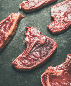 Raw uncooked beef meat steak cuts over black background