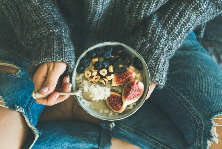 Woman in shabby jeans and sweater eating breakfast, square crop