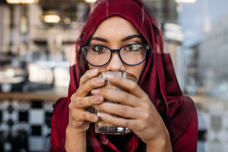 Muslim woman having coffee at cafe