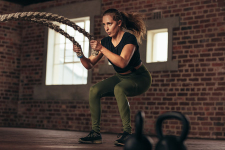 Fitness woman using battle ropes for exercising