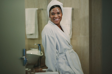Woman in bathrobe standing in bathroom