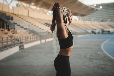 Female athlete warming up before a run in the stadium