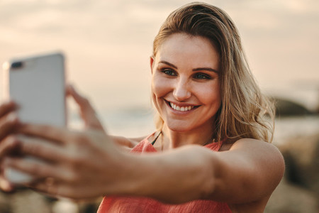 Woman taking selfie standing at the beach
