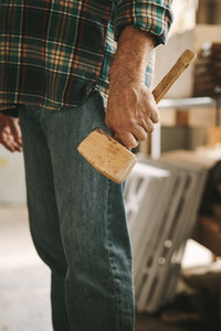 Carpenter with mallet hammer at workshop
