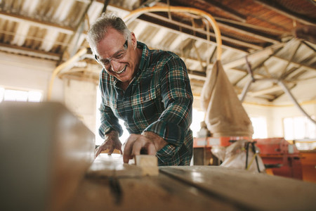 Smiling mature man working in carpentry workshop
