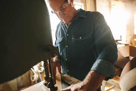 Senior male carpenter working on band saw machine