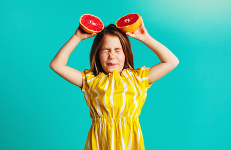 Girl holding grapefruit with dislike expressions