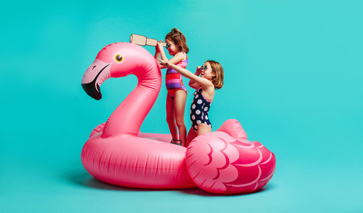 Cute girls in swimwear playing on inflatable mattress