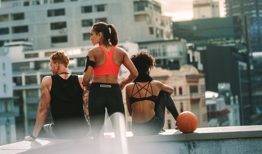 Rear view of athletic man and women sitting on rooftop