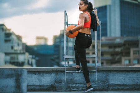 Female athlete standing on rooftop staircase looking away