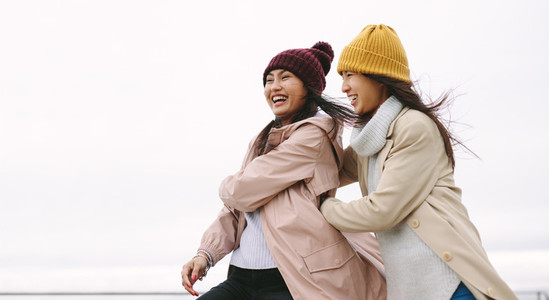 Two asian women in winter clothes standing together outdoors