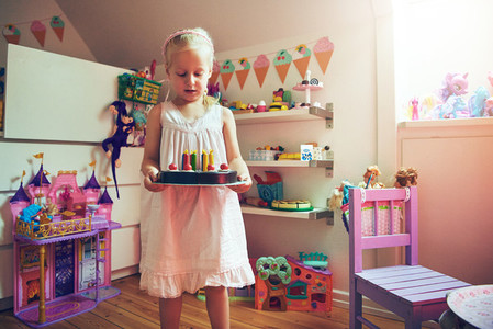 Adorable little girl standing with toy cake