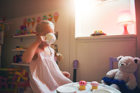 Girl drinking tea with her toy bear