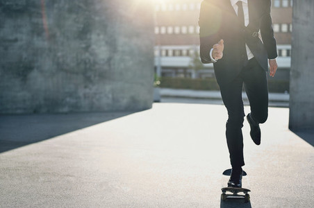 Unrecognizable man in suit riding a skateboard