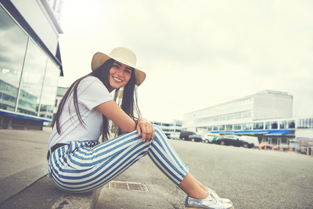 Woman seated on curb wearing striped pants