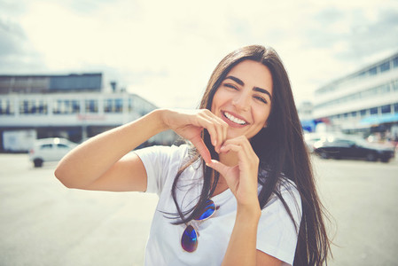 Laughing young woman making a heart gesture