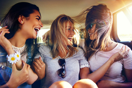 Three vivacious young women in the back of a car