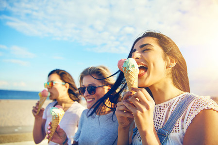 Three young woman eating ice cream at the seaside