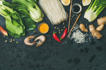 Flat lay of Asian cuisine ingredients over black background copy space