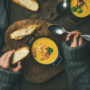 Woman in sweater eating corn soup with shrimps  square crop