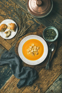 Warming pumpkin cream soup with croutons and seeds  vertical composition