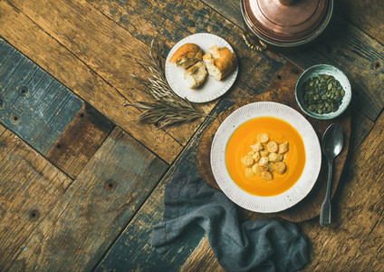 Warming pumpkin cream soup with croutons and seeds copy space