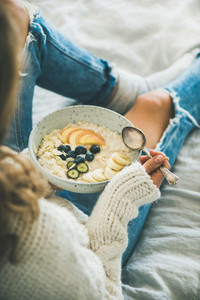 Woman in shabby jeans and sweater eating vegan breakfast