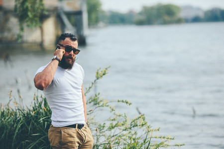 American Bearded Man using phone near the river