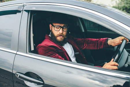 Man with a beard driving a car