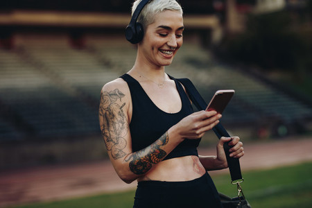 Smiling female athlete looking at mobile phone