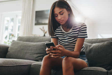 Girl using mobile phone sitting on couch