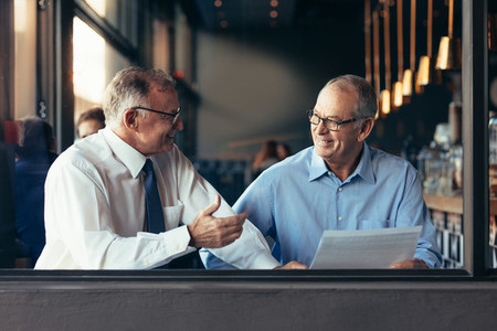 Mature business partners working together at a cafe