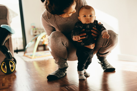 Woman holding her baby squatting on floor