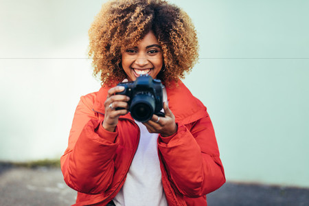 Smiling woman traveller taking photos outdoors