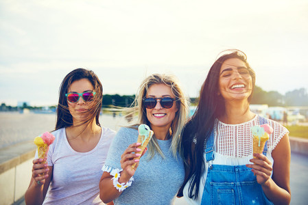Three joyful young girlfriends on a promenade