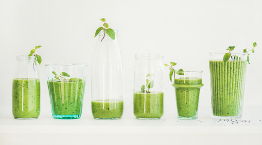 Matcha green smoothie with chia seeds in glasses and bottles
