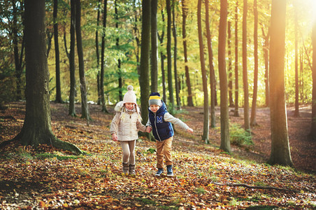 Two kids walking through the green forest