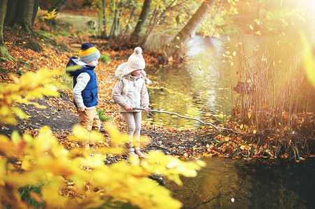 Two kids with branch near the pond